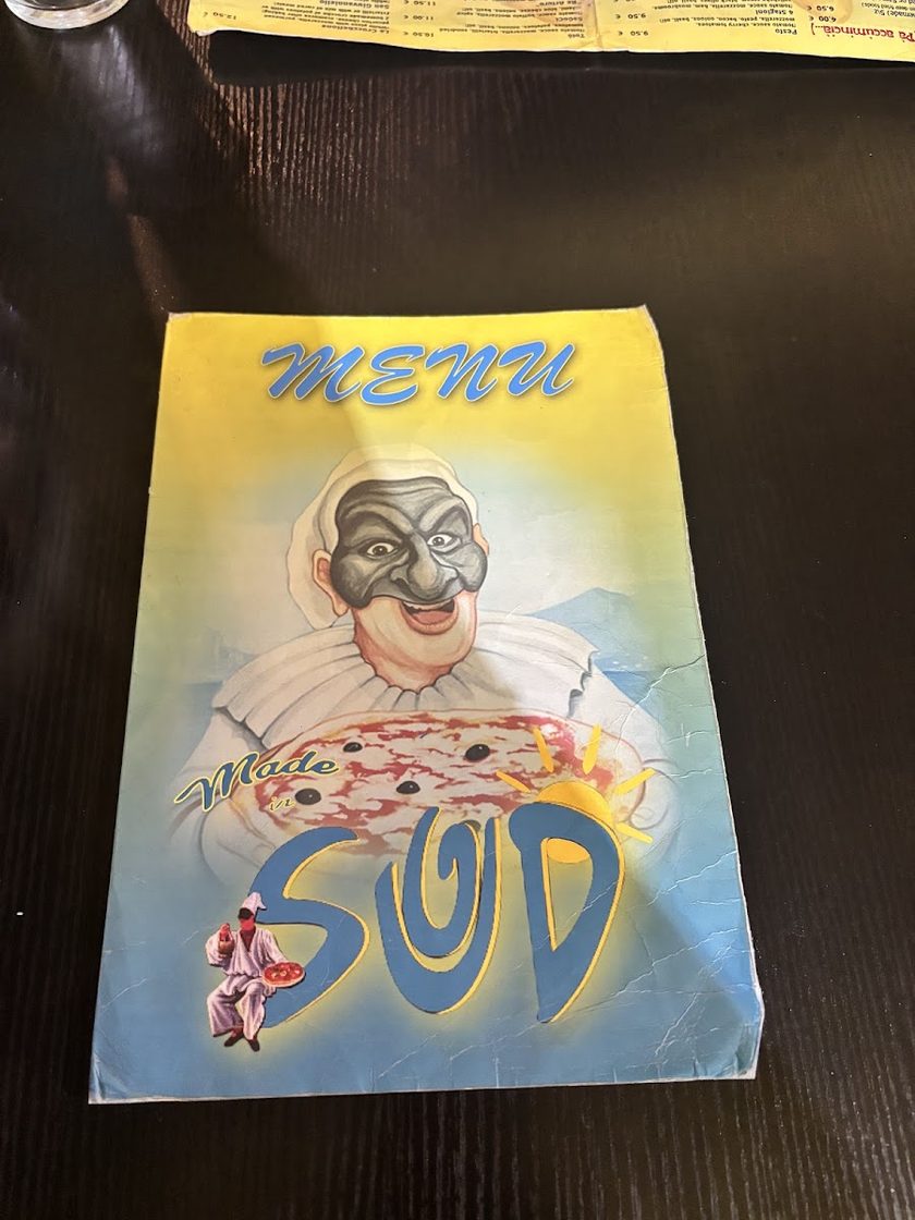 The restaurant's printed menu cover, yellow with a blue drawing of a moustachioed pizzaiolo above the words Made in Sud